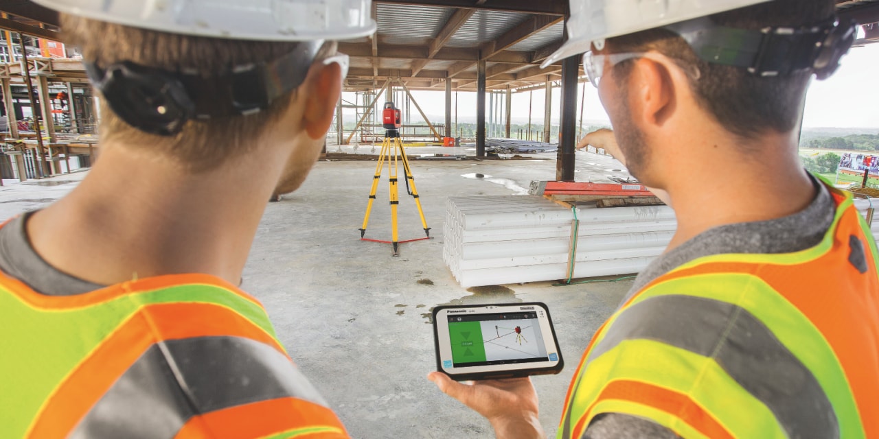Two workers onsite using a Total Station to position MEP supports